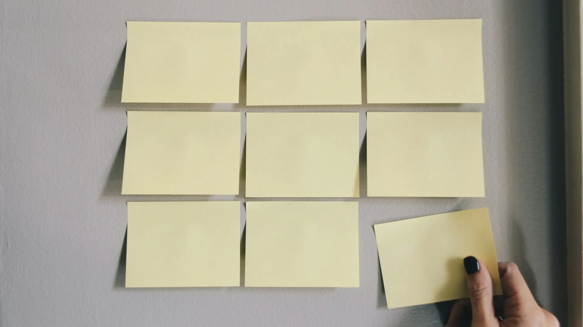 Six sticky notes in two rows, three in each row. The bottom right note is being pulled by a human hand.